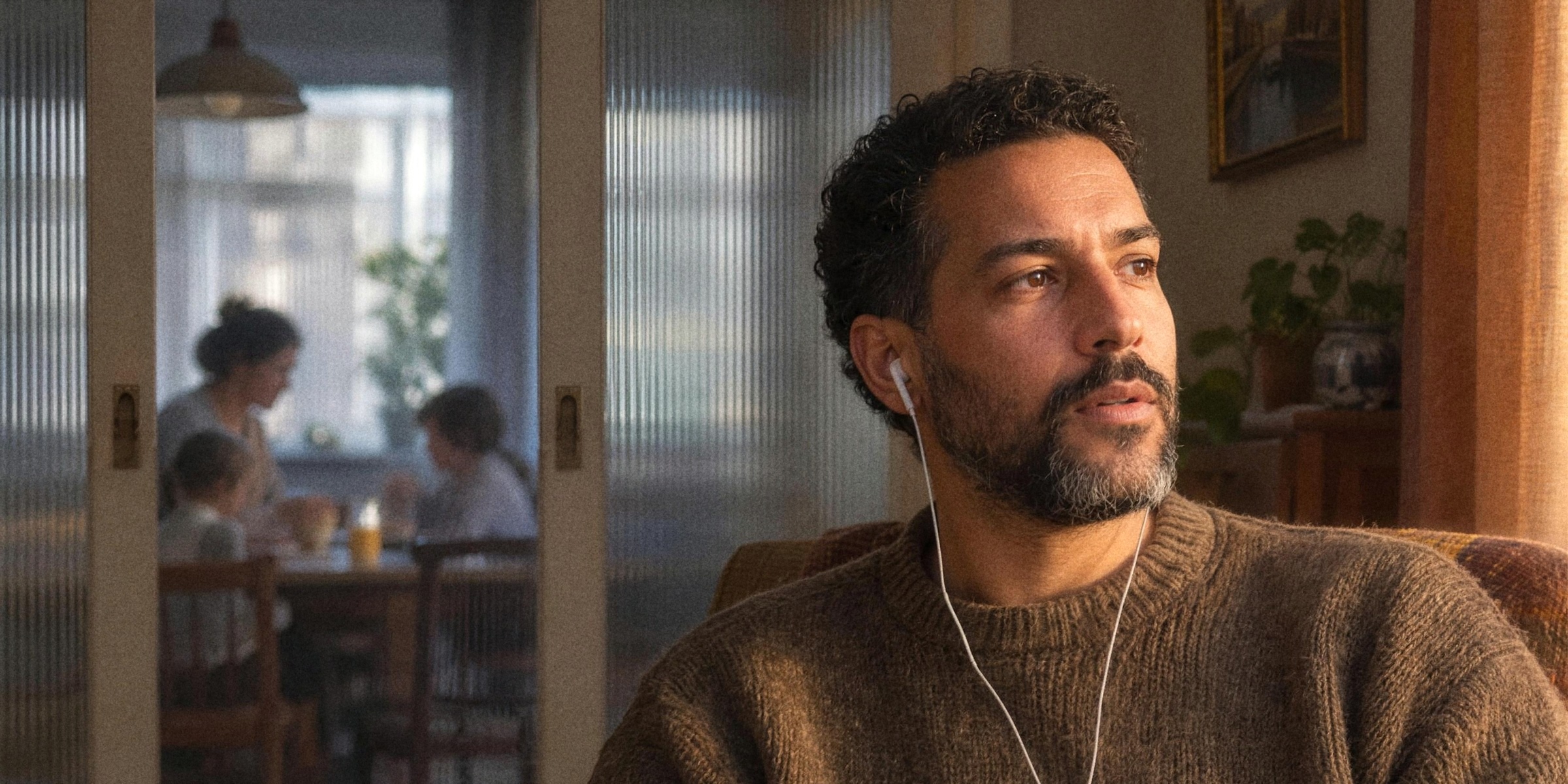 A man at home in an armchair listening on wired earphones