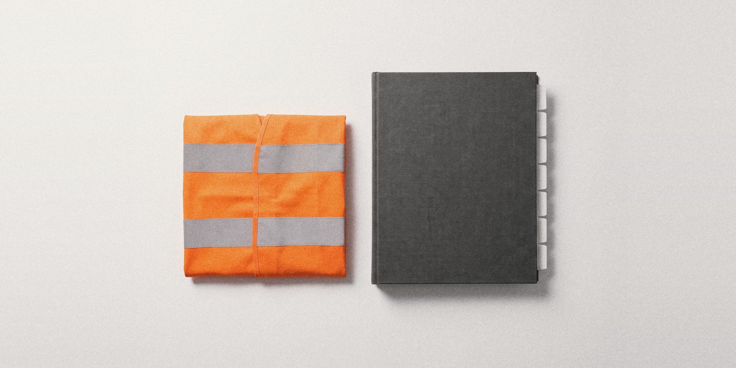 A folded hi-vis vest beside a closed binder with index tabs