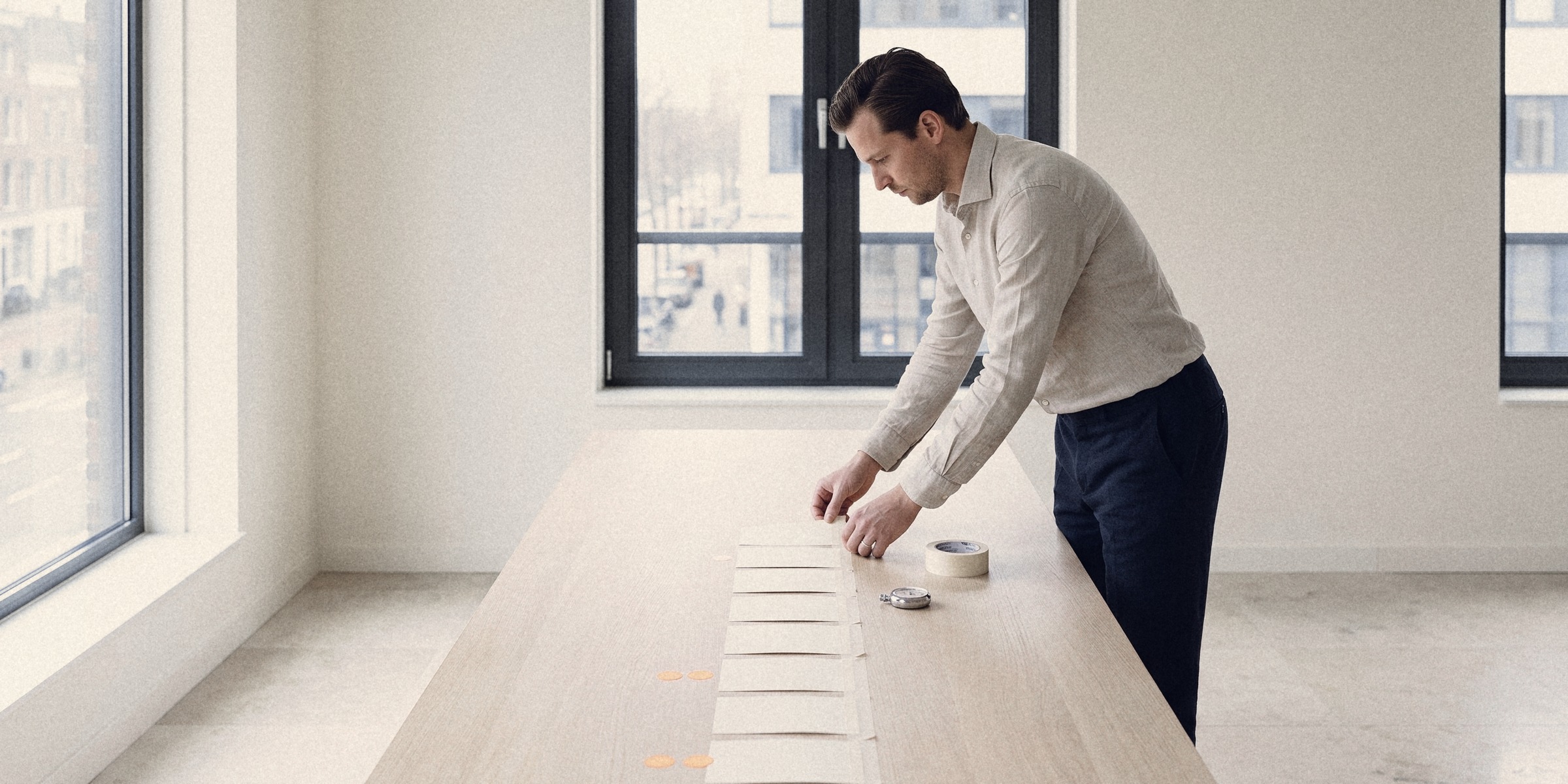 A recruiter placing the next blank index card in a taped line of cards along an oak table