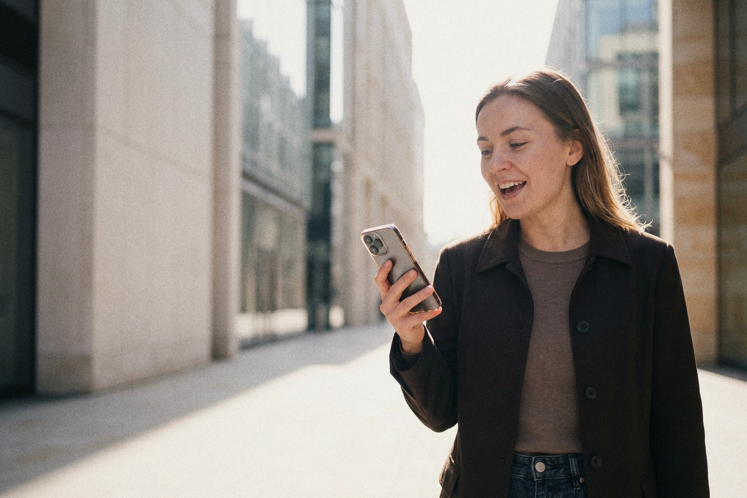 A woman on a city street reading her phone
