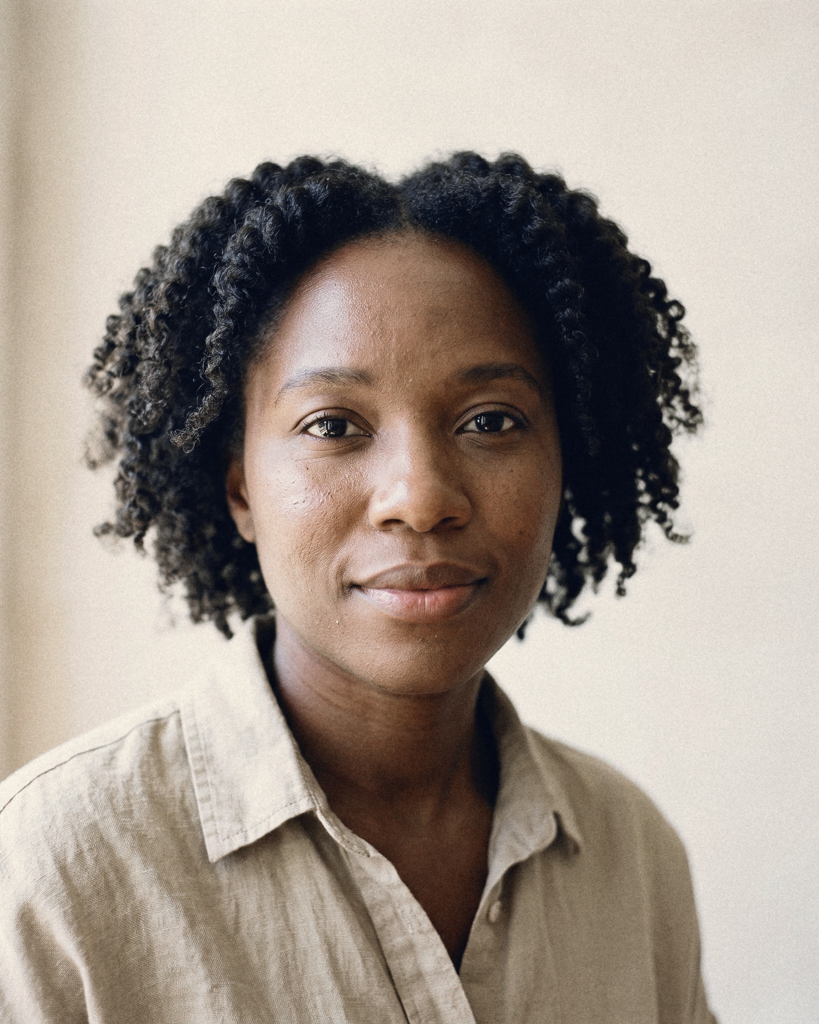 A woman with natural curly hair in a beige linen shirt