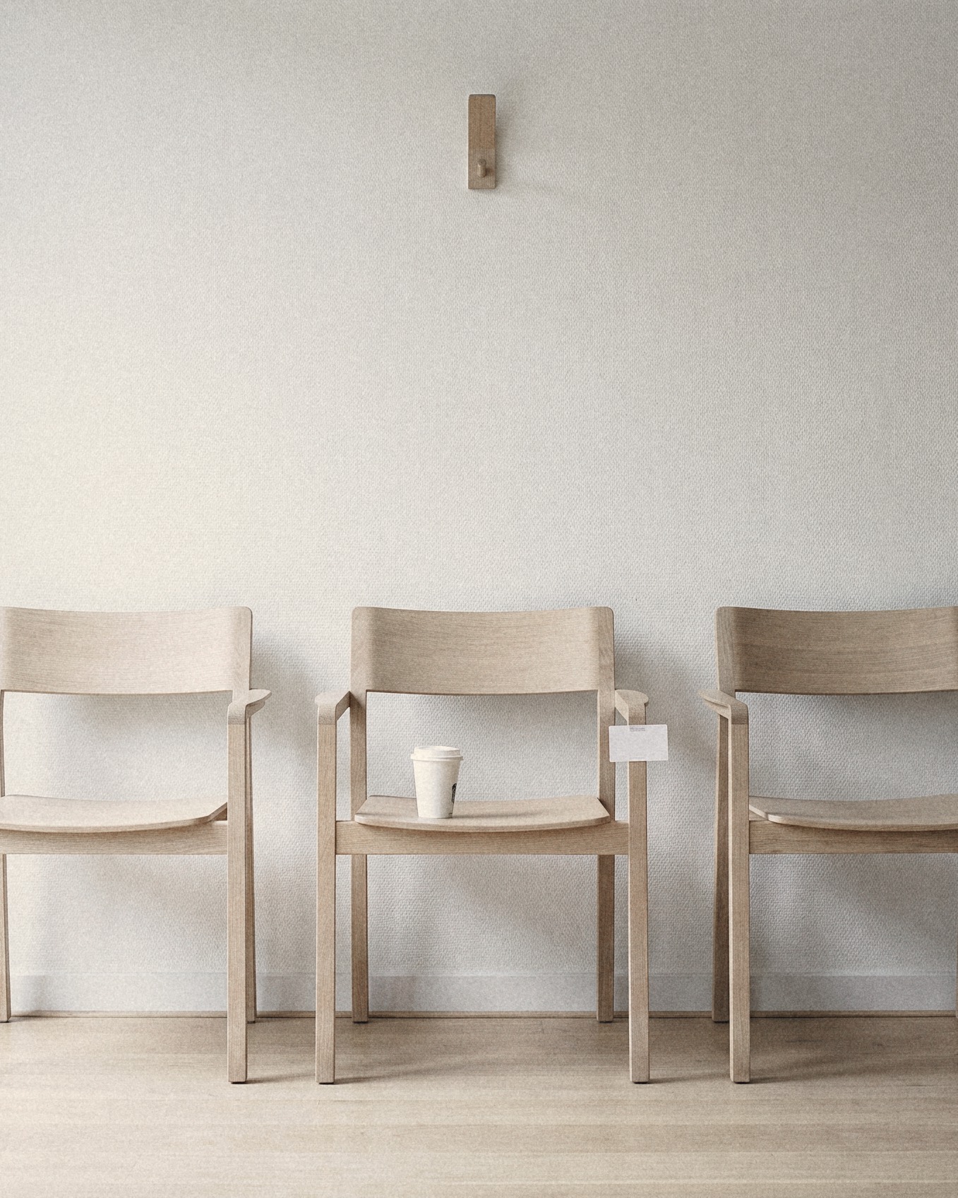 Three empty chairs in an agency waiting area, a half full coffee cup left on the middle one
