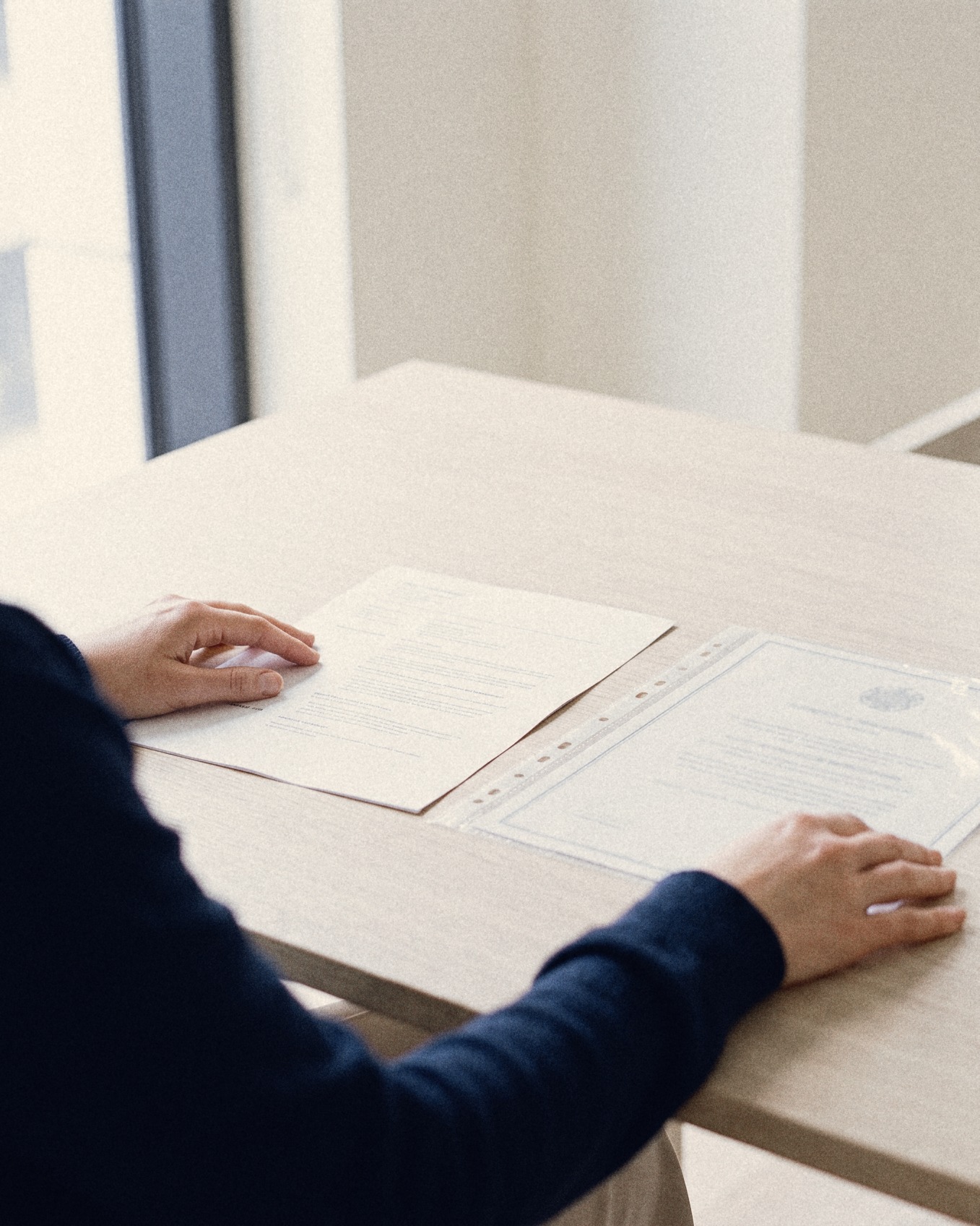 Een recruiter vergelijkt een geprint cv met een origineel diploma in een plastic hoes
